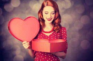 žena s úsměvěm hledí do krabice ve tvaru srdce