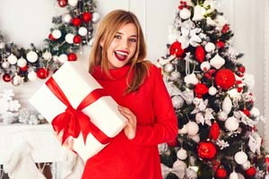 žena s dárkem u vánočního stromečku